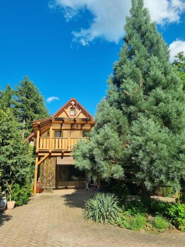 a log home with a large pine tree at Bámbi Apartman in Harsány