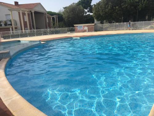 une grande piscine d'eau bleue en face d'une maison dans l'établissement Hollywood, piscine, lac et golf, à Saint-Jean-de-Monts