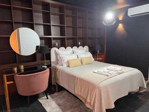 a bedroom with a bed with a mirror and a chair at Casa Maramar in Angra do Heroísmo
