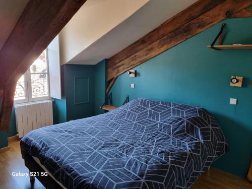 une chambre avec un lit avec un mur bleu dans l'établissement Petit nid, à Laroquebrou
