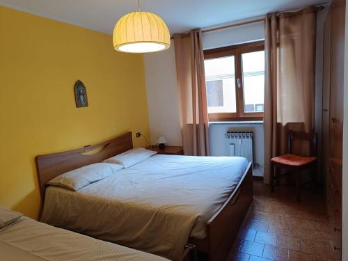 a bedroom with two beds and a large window at Appartamento Pizzo Cassandra in Chiesa in Valmalenco