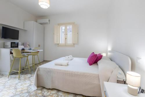 a white bedroom with a bed and a kitchen at Appartamento Liolà in Scicli