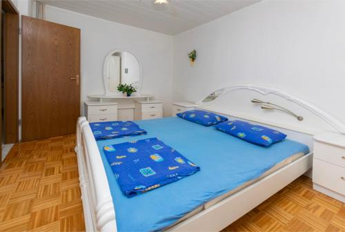 a bedroom with a bed with blue sheets and a mirror at Apartments First row in Zavalatica