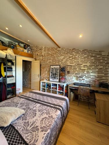 une chambre avec un lit et un mur de briques dans l'établissement Maison chaleureuse, à Rabastens