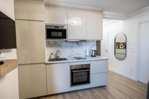 une cuisine avec des armoires blanches et un évier dans l'établissement Appartement Luxueux à 30min de la Tour Eiffel, à Asnières-sur-Seine