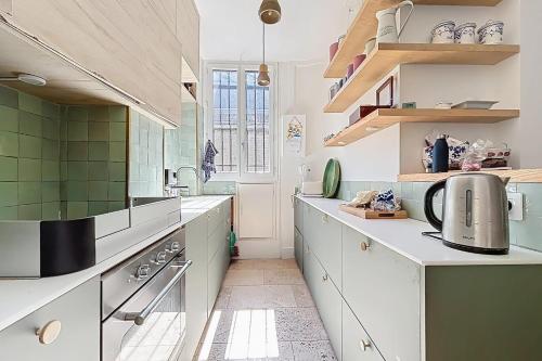 une cuisine avec des placards blancs et du carrelage vert dans l'établissement Large family duplex near Parc Monceau, à Paris