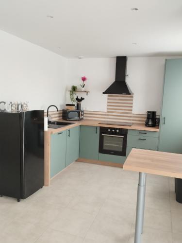 - une cuisine avec des placards verts et un réfrigérateur noir dans l'établissement Maison de vacances à la plage, à Créances