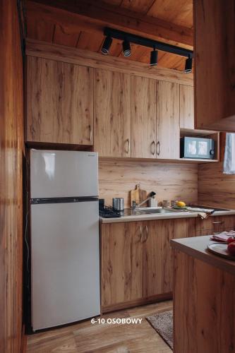 a kitchen with a white refrigerator and wooden cabinets at Słoneczne domki in Dębki