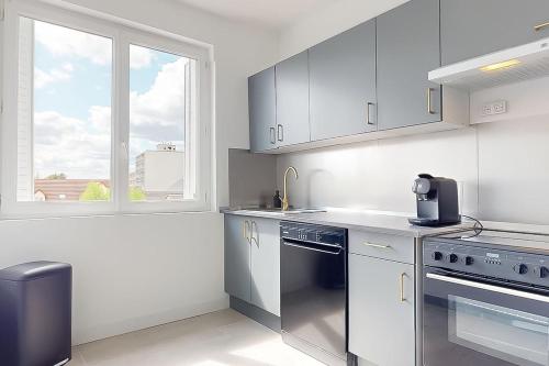 d'une cuisine équipée d'appareils en acier inoxydable et d'une fenêtre. dans l'établissement Spacieux appartement proche centre - hôpital, à Châteauroux