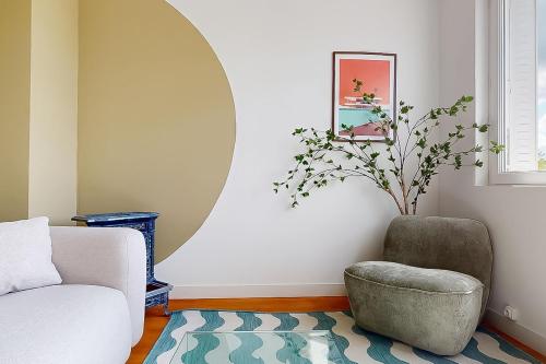 a living room with a chair and a mirror at Spacieux appartement proche centre - hôpital in Châteauroux