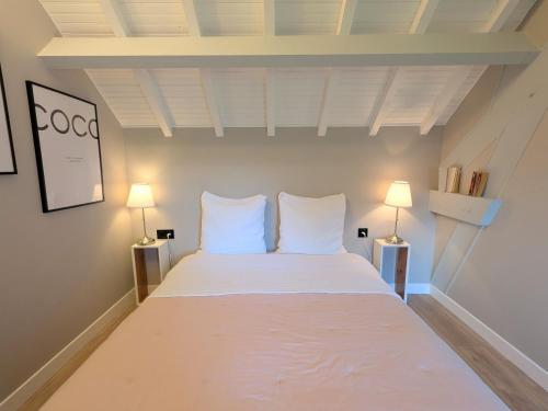 a bedroom with a large white bed with two lamps at Le Clos d Emilie in Saint-Marcel
