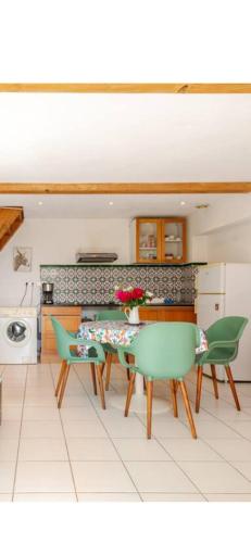 une cuisine avec une table et des chaises vertes dans l'établissement Le Séville 20mn des plages climatisé, à Béziers