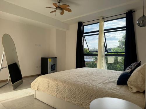 ein Schlafzimmer mit einem Bett und einem großen Fenster in der Unterkunft Dormitorio con baño privado es Tu descanso en el corazón de San Salvador in San Salvador