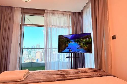 a bedroom with a large window with a flat screen tv at Seaview White 1Br Balcony in Manama