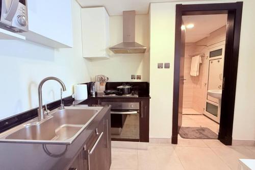 a kitchen with a sink and a stove at Seaview White 1Br Balcony in Manama