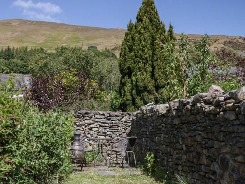 a stone wall with a chair next to a stone fence at Badgers in Sedbergh