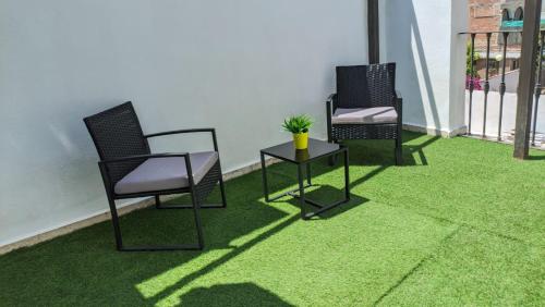 two chairs and a table on a green carpet at Hotel María de Molina in Úbeda