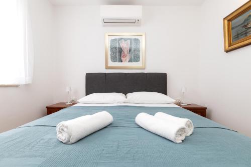 a bedroom with a blue bed with two white towels at BELLAVISTA apartman Punta in Veli Lošinj