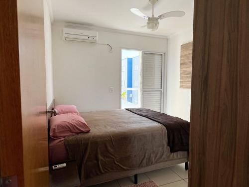 a bedroom with a bed with a fan and a window at Apartamento aconchegante com ótima localização! in Brotas