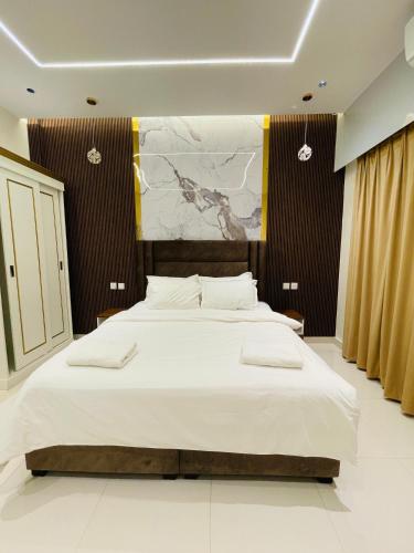 a bedroom with a large bed and a painting on the wall at Mabahj Garnatha Hotel Apartments in Sohar