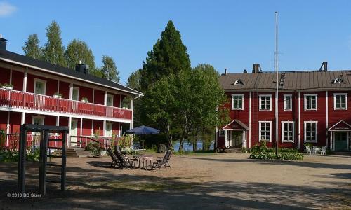 un grande edificio rosso con sedie e tavoli di fronte ad esso di Viljamaan kartano a Kortteinen