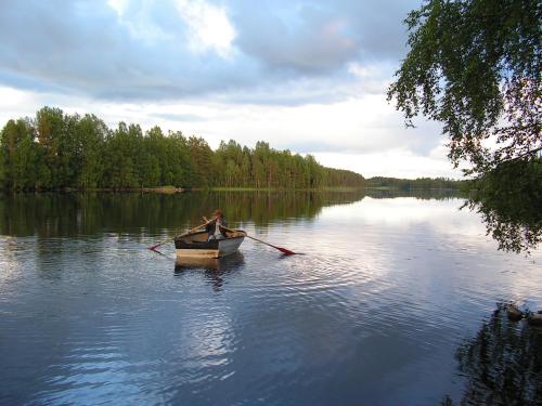 Um homem está a remar um barco num lago. em Viljamaan kartano em Kortteinen