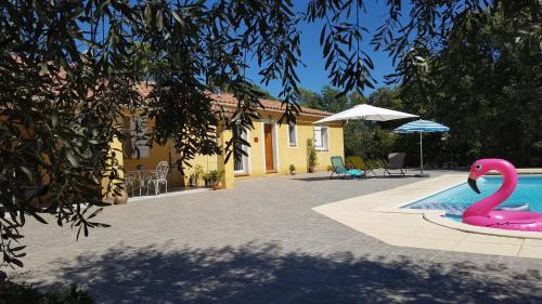 un cygne rose dans une piscine à côté d'une maison dans l'établissement Le cigalon, à Saint-Maximin-la-Sainte-Baume