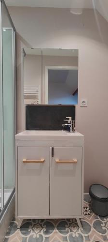 - une cuisine blanche avec un évier et un miroir dans l'établissement confort et tranquillité à Fougères - studio tout équipé, à Fougères