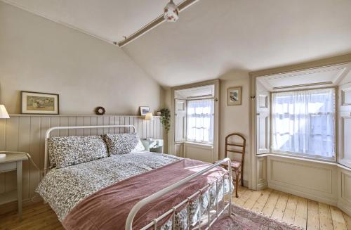 ein Schlafzimmer mit einem Bett und zwei Fenstern in der Unterkunft Captains Cottage in Donaghadee