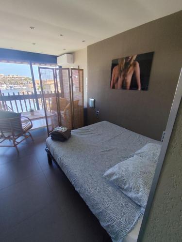 une chambre avec un lit avec un tableau sur le mur dans l'établissement Naturiste Cap d'Agde Port Vénus 212, au Cap d'Agde
