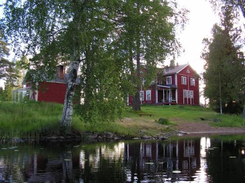 een rood huis naast een waterlichaam bij Viljamaan kartano in Kortteinen