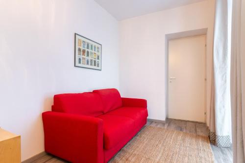 a red couch in a room with a door at Cascina Abbona - Cascina Storica a 15 min. da Alba in Canove
