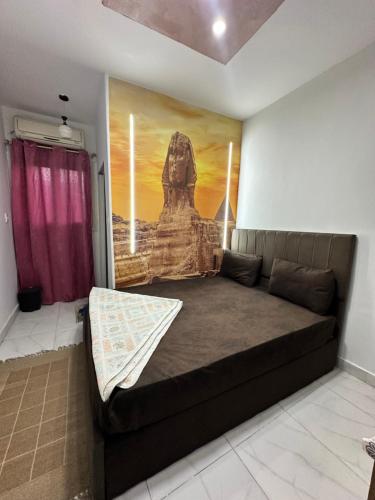 ein Bett in einem Zimmer mit einem Gemälde an der Wand in der Unterkunft Abo Stait - Pyramid View Homestay in Kairo