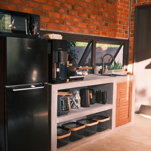 a kitchen with a black refrigerator and a brick wall at The Hectar Private villa in Janda Baik in Bentong