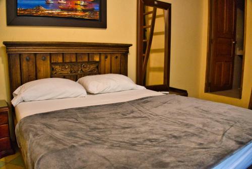 a bedroom with a large bed with a wooden headboard at La Brisa Loca Hostel in Santa Marta