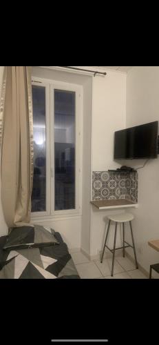 un salon avec une télévision, une chaise et une fenêtre dans l'établissement Les 4 Studettes, à Marseille