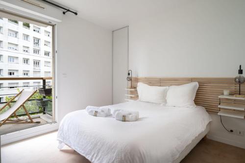 une chambre avec un lit blanc et une grande fenêtre dans l'établissement Appartement Cayla - Welkeys, à Courbevoie