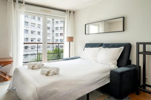 une chambre avec un grand lit et une grande fenêtre dans l'établissement Appartement Cayla - Welkeys, à Courbevoie