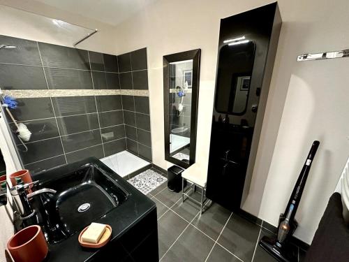 La salle de bains est pourvue d'un lavabo noir et d'une douche. dans l'établissement Appartement Vue Bassin - Arcachon, à Arcachon