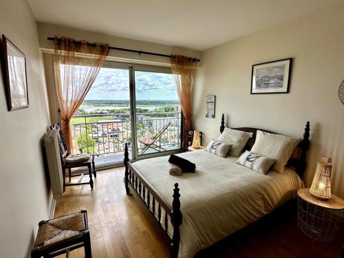 une chambre avec un grand lit et une grande fenêtre dans l'établissement Appartement Vue Bassin - Arcachon, à Arcachon
