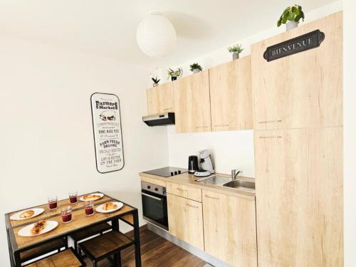 une cuisine avec des placards en bois et une table avec de la nourriture. dans l'établissement Passage Secret - Idéal Pro, Couples, Familles & Amis - Le calme en Hypercentre - Wifi Haut Débit - Netflix - Machine à laver - Gare, Cathédrale, Commerces, Restaurants & Transports en commun à moins de 10 Minutes à pied, à Reims