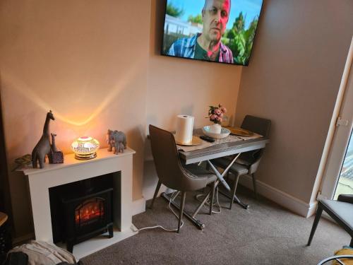 a living room with a table and a tv on the wall at Apartment Mary Street in Porthcawl