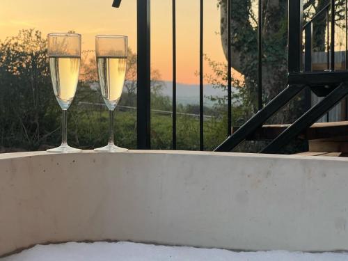 two glasses of champagne sitting on a ledge with the sunset at Ashmead Shepherds hut in Whimple