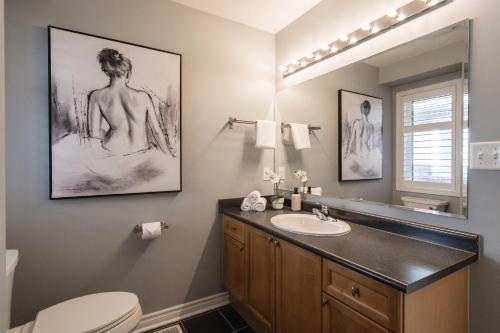 a bathroom with a sink and a toilet and a mirror at Cozy 5 Bedroom House near Toronto Airport in Mississauga