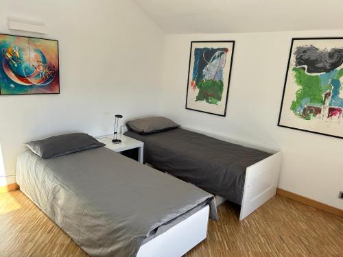 two beds in a room with paintings on the wall at Centro Stazione Attico in Turin