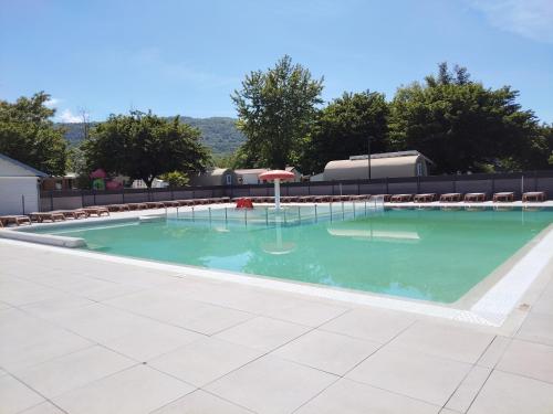 - une piscine avec un parasol et des chaises dans l'établissement Mobil Home for chilling out Camping Park ***, à Foix