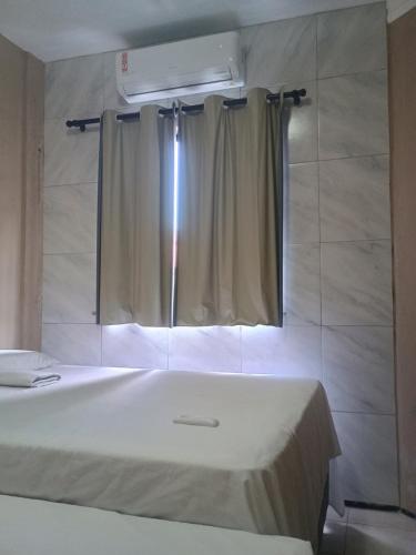 a bedroom with a bed and a window with a curtain at Apto Praia do Meio in São José de Ribamar