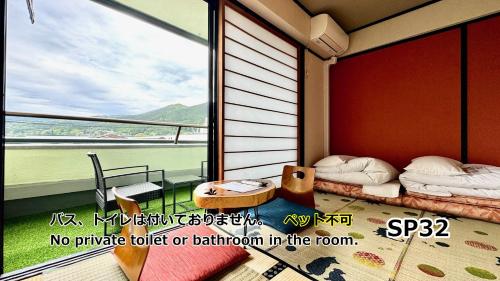 a room with a balcony with two beds and a window at Yufuin Akarinoyado in Yufuin