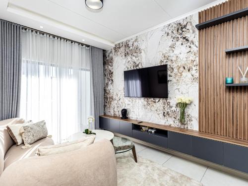 a living room with a couch and a tv on a wall at Thetan's Home Away From Home in Midrand