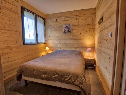 une chambre avec un lit dans un mur en bois dans l'établissement Charmant appart. au pied des pistes, proche centre, avec terrasse, casier à skis et parking - FR-1-505-106, à Crest-Voland